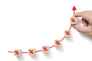 Interest rate financial and mortgage rates concept. Hand putting wood cube block increasing with icon percentage symbol upward direction