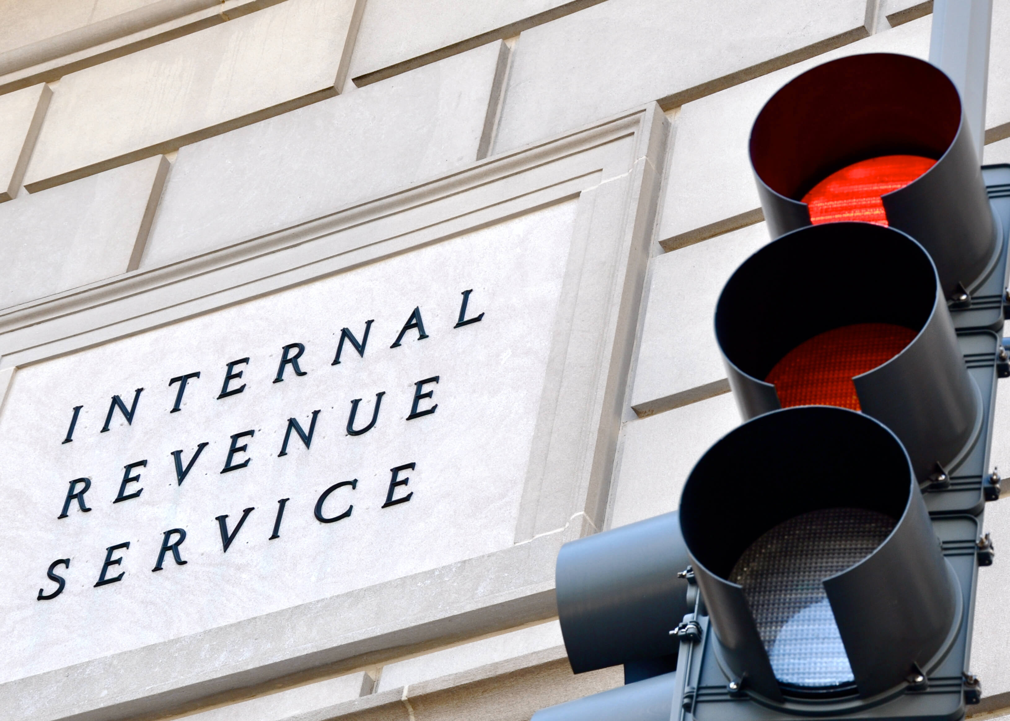 Internal Revenue Service sign with a traffic signal in the foreground indicating a red light.