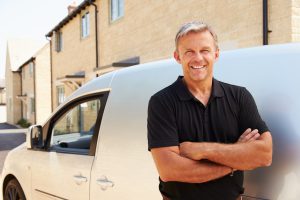 Portrait of middle aged tradesman standing by his van