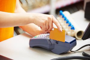 sale assistant cashier accepting credit bank card and using payment terminal for purchase