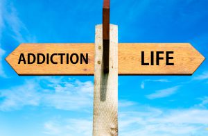 Wooden signpost with two opposite arrows over clear blue sky, Addiction and Life signs, Choice conceptual image