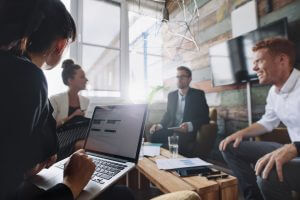 Businesswoman working on laptop while sitting in meeting with colleague. Business people in meeting room.