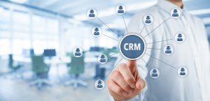 Customer relationship management (CRM) concept. Businessman click on virtual scheme representing CRM (or customer service). Wide banner composition with office in background."n
