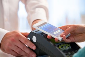 Wireless payment using smartphone and NFC technology. Close up. Customer paying with smart phone in pharmacy. Close Up shopping