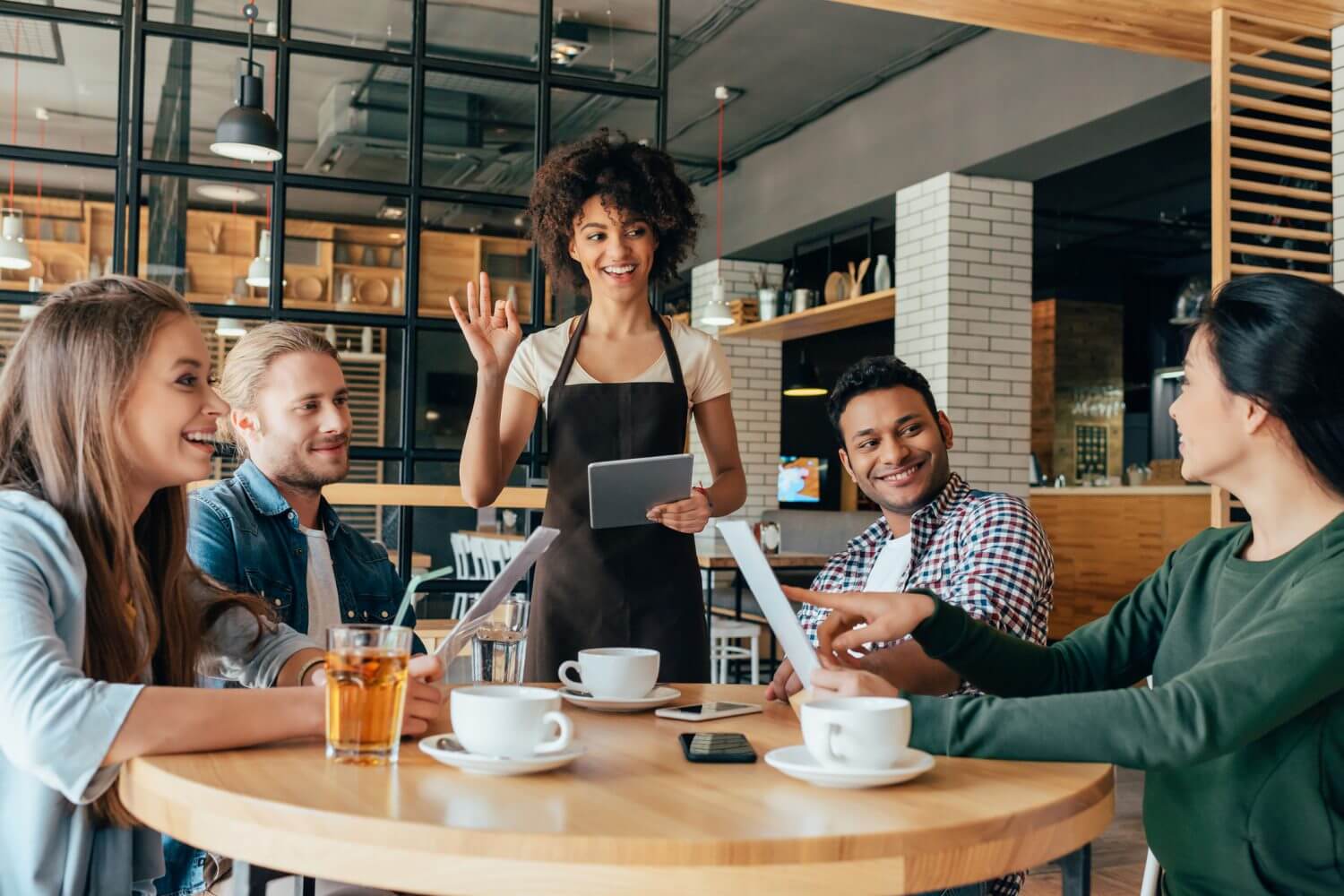 Young african american woman waitress taking orders from clients in cafe.