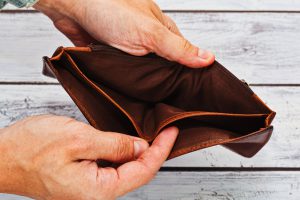 Person holding in hands totally empty leather wallet - crisis and poverty symbol